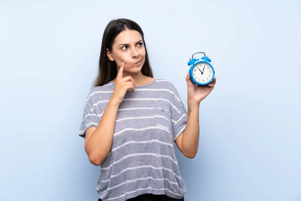 Joven Morena Sobre Fondo Azul Aislado Sosteniendo Reloj Despertador Vintage — Foto de Stock