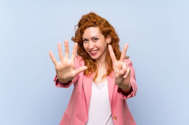 Kızıl saçlı kadın, mavi duvarın üstünde, parmaklarıyla yediyi sayıyor.