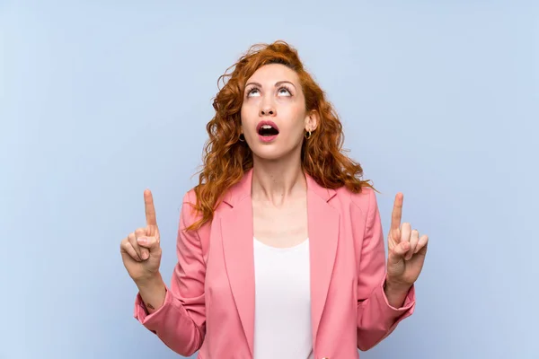 Redhead Woman Suit Isolated Blue Wall Surprised Pointing — Stock Photo, Image