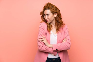 Izole pembe duvar ayakta ve bir fikir düşünme üzerinde takım elbiseredhead kadın