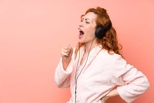 Femme rousse en robe de chambre écouter de la musique — Photo