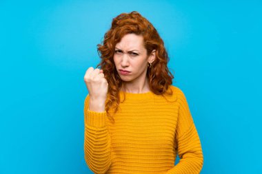 Öfkeli, sarı kazaklı, kızıl saçlı kadın.