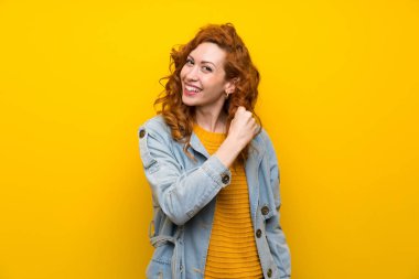 İzole sarı arka plan üzerinde Redhead kadın bir zafer kutluyor