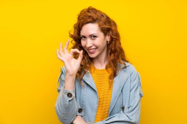 Izole sarı arka plan üzerinde Redhead kadın parmakları ile ok işareti gösteren