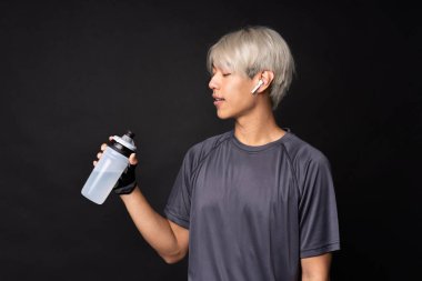 Genç Asyalı sporcu, soyutlanmış siyah arka planda.