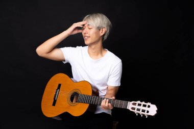 Siyah arka planda gitar çalan Asyalı genç bir adam bir şey fark etti ve çözüme niyetlendi.