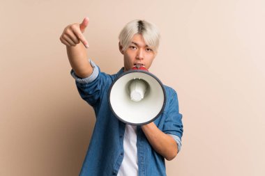 Asyalı genç bir adam izole edilmiş arka planda megafondan bağırıyor.