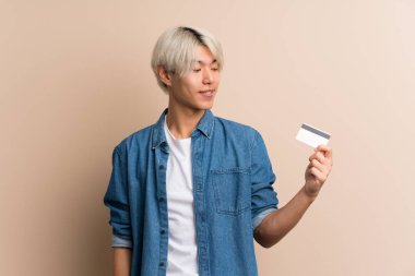Soyutlanmış geçmişi olan genç bir Asyalı kredi kartı tutuyor.