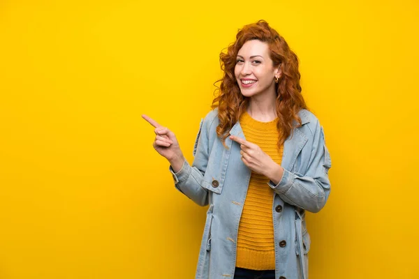 Redhead Žena Izolovaném Žlutém Pozadí Ukazující Prstem Stranu — Stock fotografie