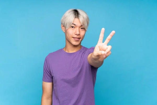 Joven Asiático Hombre Sobre Aislado Azul Fondo Sonriendo Mostrando Victoria — Foto de Stock