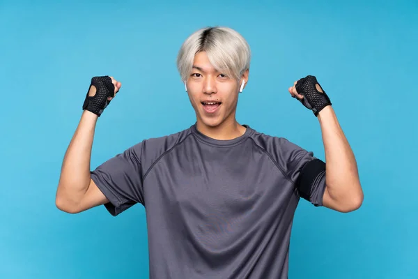 Mladý Asijský Sport Muž Přes Izolované Modré Pozadí Slaví Vítězství — Stock fotografie