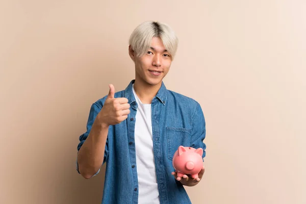 Fiatal Ázsiai Férfi Elszigetelt Háttér Gazdaság Egy Nagy Malac Bank — Stock Fotó