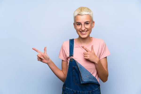 Teenagerka Předevčelemi Modré Stěně Ukazující Prst Stranu — Stock fotografie