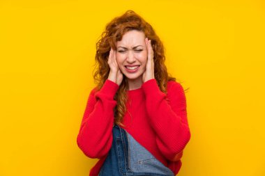 Kızıl saçlı kadın, izole edilmiş sarı duvarlı, mutsuz ve hayal kırıklığına uğramış bir kadın. Olumsuz yüz ifadesi