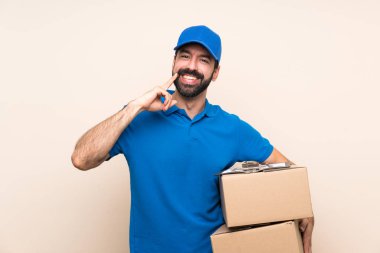 Arkaplanda sakallı teslimatçı mutlu ve hoş bir ifadeyle gülümsüyor.