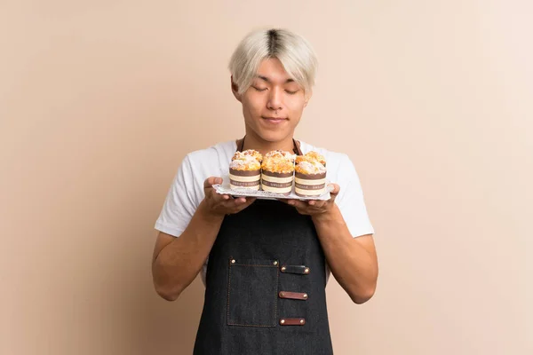 Joven Asiático Hombre Sobre Aislado Fondo Celebración Mini Pasteles Disfrutando — Foto de Stock