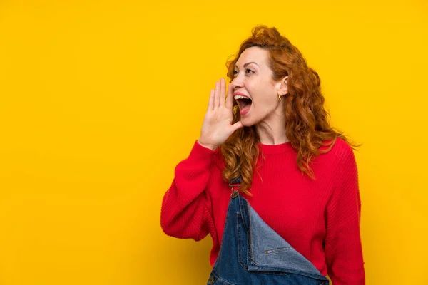 Redhead Vrouw Met Overalls Geïsoleerde Gele Muur Schreeuwen Met Mond — Stockfoto