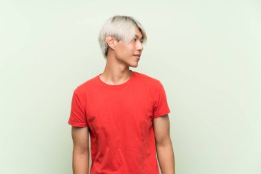 Tecrit edilmiş yeşil arka planda genç Asyalı bir adam.