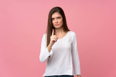 Soyutlanmış pembe arka planı olan genç bir kadın hayal kırıklığına uğramış ve ön tarafı işaret ediyor.