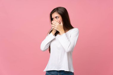 Soyutlanmış pembe arka planda genç bir kadın ağzını kapatıyor ve yan tarafa bakıyor.