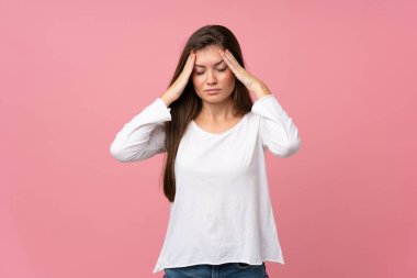 Soyutlanmış pembe arka planda baş ağrısı olan genç bir kadın.
