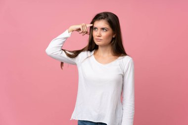 Soyutlanmış pembe arka planda genç bir kadın deliliğin jestini yapıyor. Parmağını kafaya koyuyor.