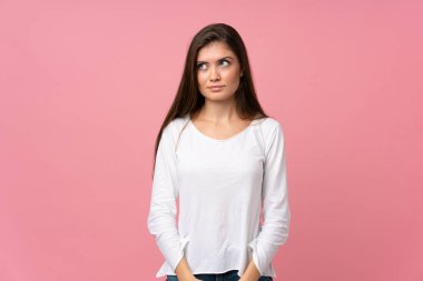 Soyutlanmış pembe arka planda genç bir kadın şüpheli hareketler yapıyor.