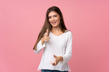 Soyutlanmış pembe arka planda genç bir kadın ön tarafı gösteriyor ve gülümsüyor.