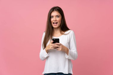 Soyutlanmış pembe arka planı olan genç bir kadın şaşırdı ve bir mesaj gönderiyor.