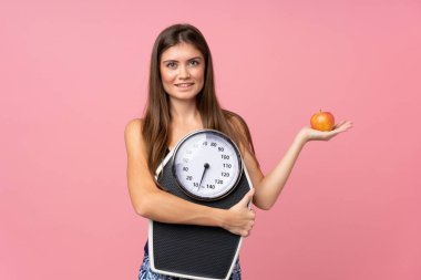 Tartı makinesi olan genç bir kız ve izole edilmiş bir elma.