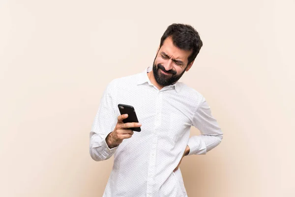 Joven Con Barba Sosteniendo Móvil Sufriendo Dolor Espalda Por Haber —  Fotos de Stock