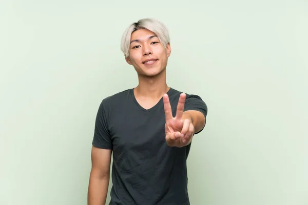 Joven Asiático Hombre Sobre Aislado Verde Fondo Sonriendo Mostrando Victoria — Foto de Stock
