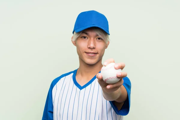 Mladý asijský muž hraje baseball přes izolované zelené pozadí — Stock fotografie