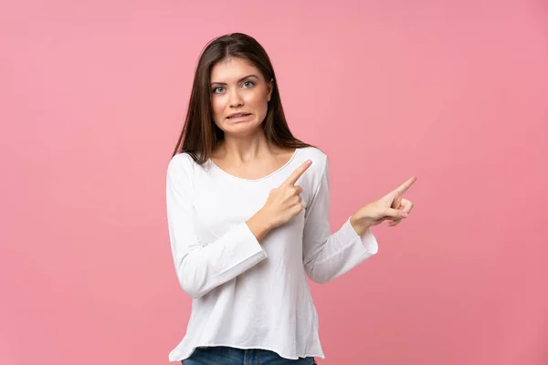 Jonge Vrouw Geïsoleerde Roze Achtergrond Bang Wijzen Naar Zijkant — Stockfoto