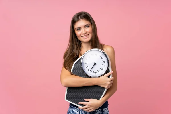 Tecrit edilmiş pembe arka planda tartı makinesi olan genç bir kız. — Stok fotoğraf