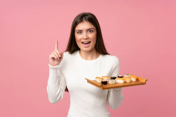 Chica Joven Con Sushi Sobre Fondo Rosa Aislado Señalando Una —  Fotos de Stock