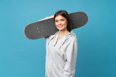 Genç bir kadın kaykayla izole edilmiş mavi arka plan.