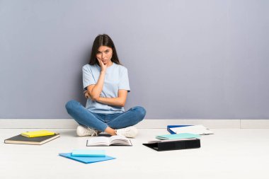 Yerde bir sürü kitabı olan genç bir bayan öğrenci mutsuz ve hayal kırıklığına uğramış.