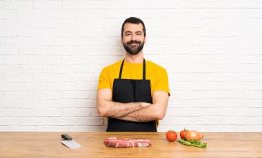 Aşçı mutfağı tutuyor, kollarını ön tarafta kavuşturuyor.