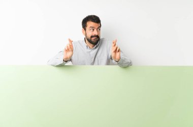 Sakallı genç yakışıklı adam elinde kocaman yeşil boş bir levhayla şans diliyor.