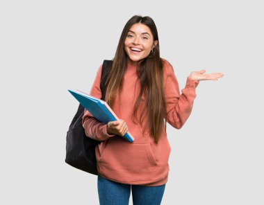 Kopyalama alanı tutan not defterleri tutan genç bir bayan. Gri arka planı iki elle kapatıyor.