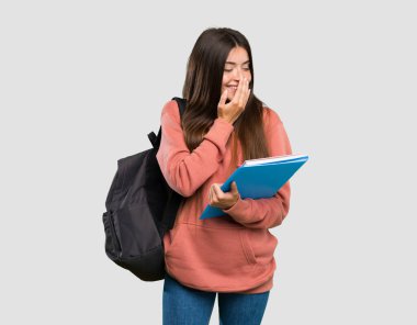 Genç öğrenci kadın izole gri arka plan üzerinde çok gülümseyen deftertutan