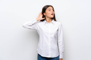 Genç kadın üzerinde izole beyaz arka plan dinleme bir şey