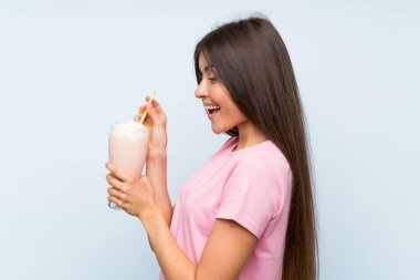 Izole mavi arka plan üzerinde çilek milkshake ile genç kadın