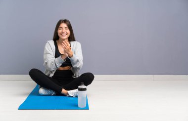 Genç sporcu kadın yerde oturmuş alkışlıyor.