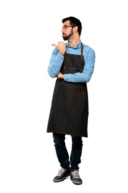 Önlüklü, mutsuz ve yalıtılmış beyaz arkaplanı işaret eden bir adamın uzun pozu.