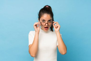 Genç esmer kız gözlüklü, soyutlanmış mavi arka plan.