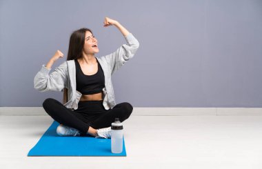 Genç spor kadın bir zafer kutluyor mat ile katta oturan