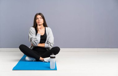 Genç spor kadın bir fikir düşünme mat ile katta oturan