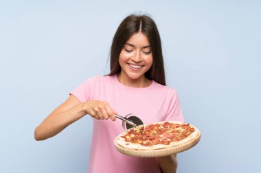 Izole mavi duvar üzerinde bir pizza tutan Pretty genç kız